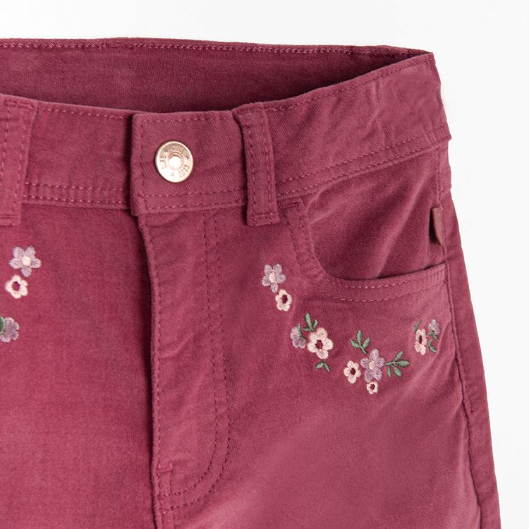 Burgundy trousers with flowers embroidered around the pockets